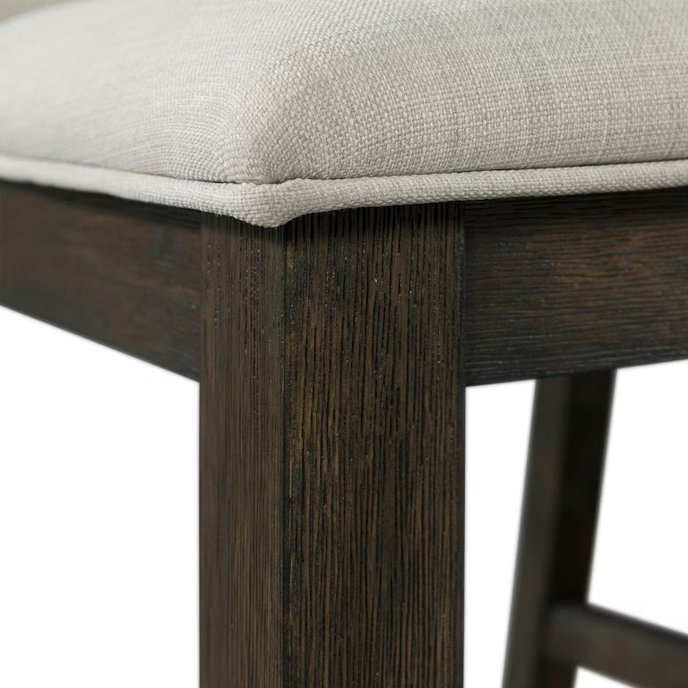 Close-up of a wooden stool with a beige cushioned seat on a white background